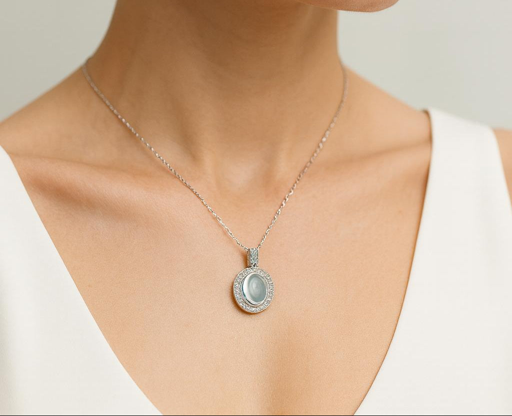 Close-up of a woman wearing a necklace with a pendant on a neutral background